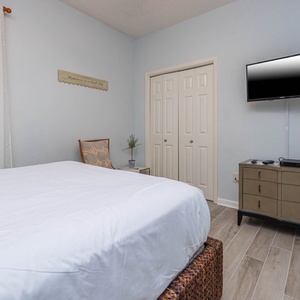 Inviting guest room featuring a plush queen bed, a stylish chair, and a TV for your entertainment