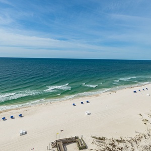 Enjoy the beach with colorful umbrellas and gentle waves, taking in the vibrant colors of the gulf waters