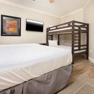 Relax in this cozy guest bedroom featuring a plushking  bed, tiwn bunk beds for extra guests, and a flat-screen TV