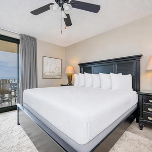King bed in the master suite offers plush comfort as you glimpse the calm beach from your balcony door