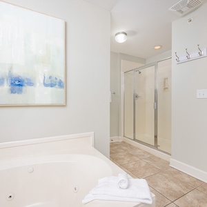Refreshing master bathroom featuring a jetted tub, walk-in shower, and soothing artwork in soft blue tones