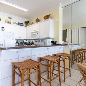 The kitchen features white cabinets, granite countertops, and a breakfast bar with stools for a relaxed dining experience