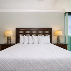 Relaxing master bedroom featuring a plush king bed, stylish lamps, and a lovely view from the balcony