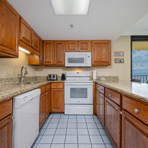 Kitchen featuring wooden cabinetry, granite countertops, and a view of the beach through large windows