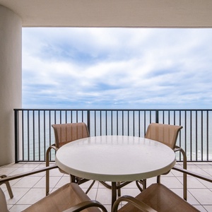 Relax on the beachfront balcony, featuring a round table and comfortable seating for relaxation