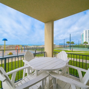 Relax on the ground floor balcony in comfortable seating, with views of the beach, splash park, and gradual entry pool area