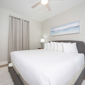 Cozy guest bedroom features a plush king bed with decorative pillows, a stylish lamp, and a wall-mounted TV for entertainment