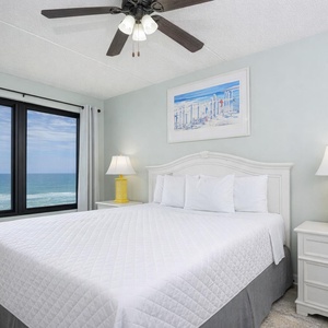 The master bedroom features a cozy queen bed and beachfront views through large windows