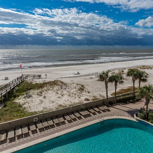 This balcony view showcases a serene pool and lazy river area surrounded by palm trees, perfect for relaxation and enjoyment