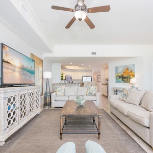 Living space featuring a large TV, cozy seating, and a view into the modern kitchen area