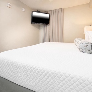Enjoy restful nights in this cozy bedroom featuring a king bed, soft lighting, and a flat-screen TV for entertainment