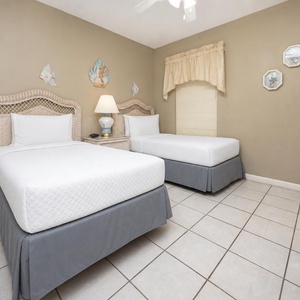Cozy guest bedroom featuring two twin beds with light bedding, a wicker headboard, and charming coastal decor accents