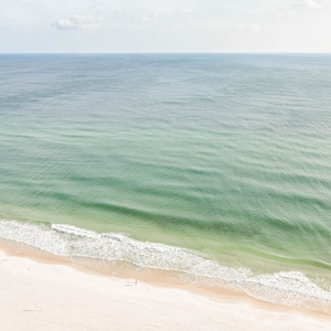This beachfront balcony view showcases serene waters and soft sands, perfect for relaxation and enjoying the coast