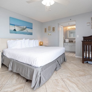 The master bedroom features a king bed, a cozy infant crib, and beach-themed decor, perfect for a relaxing getaway