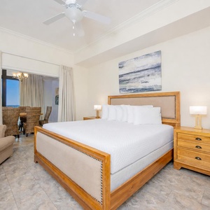 Master bedroom featuring a plush king bed, cozy twin sleeping chair, and a glimpse of a dining area through the curtains
