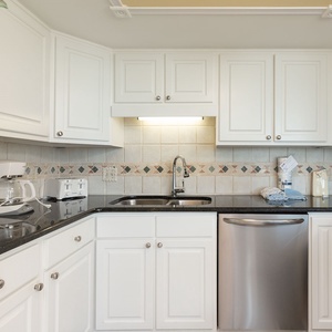 The kitchen features white cabinetry, a black countertop, and stainless appliances, creating a clean and functional space