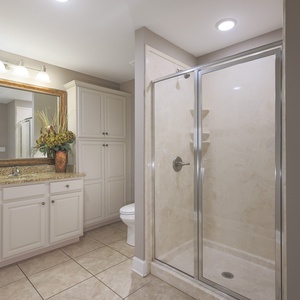 Enjoy a relaxing shower after a day at the beach in this guest bath with stylish cabinetry and spacious vanity