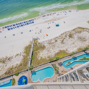 Balcony view overlooking the beach, pool area, and lazy river, perfect for relaxation and fun in the sun