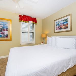 Brightly colored artwork adorns the walls of this inviting guest bedroom featuring a plush queen bed and vibrant decor