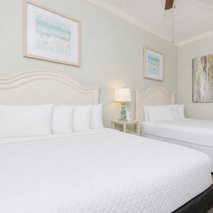 Soothing guest bedroom featuring two comfortable queen beds and coastal artwork, perfect for a relaxing stay