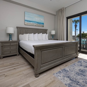 Spacious master bedroom featuring a king bed, stylish nightstands, and sliding doors leading to the patio with palm views