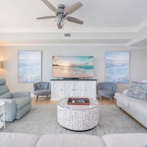 Bright and inviting living room featuring a large TV, cozy seating, and beach-inspired decor for a relaxing getaway