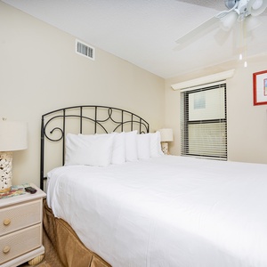 This cozy guest bedroom features a plush king bed, decorative artwork, and a charming lamp beside a nightstand