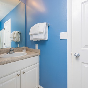 This guest bathroom features bright blue walls, a spacious vanity, and neatly arranged towels for a refreshing stay