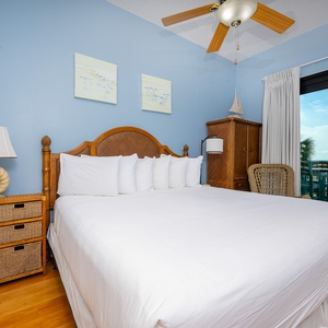 The master suite features an inviting king bed, while a balcony view adds a touch of relaxation to this tranquil bedroom