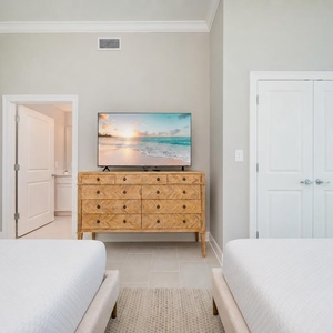 Rest in this inviting bedroom featuring two comfortable queen beds, a stylish dresser, and a large TV