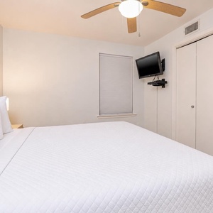 Relax in the comfortable bedroom featuring a king-sized bed, a TV, and soft lighting for a restful retreat