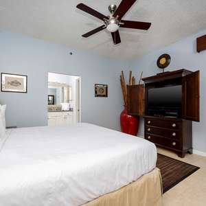 Master bedroom featuring a king bed, a wooden armoire with a TV, and a view of the water through sliding glass doors