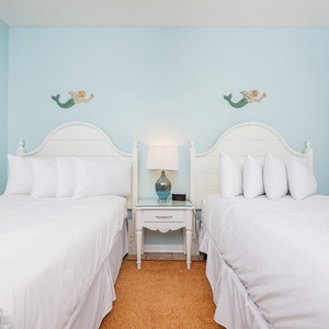 Brightly colored walls complement two double beds, creating a cheerful and inviting guest room atmosphere