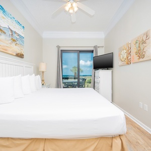 Master bedroom featuring a king bed, a TV, and access to a balcony with views of the beach and gulf