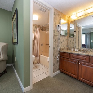 A cozy corner features a plush armchair beside the master bath with a tub/shower combo and a granite-topped vanity