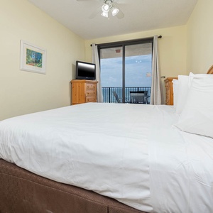 Relax in this inviting master bedroom featuring a king bed, a TV, and beachfront balcony access