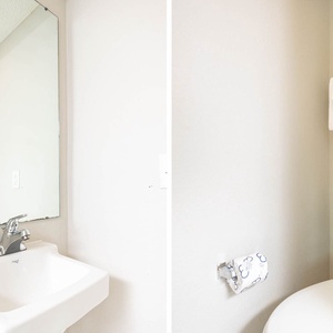 Fresh towels hang above the sink in this half bath, complemented by a vibrant piece of art, creating a welcoming atmosphere