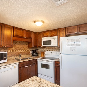 The kitchen features rich wooden cabinetry, granite countertops, and essential appliances for a delightful cooking experience