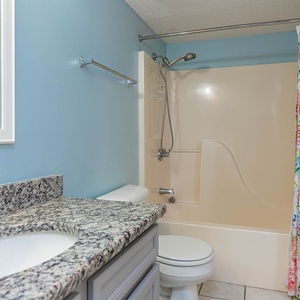 Bright bathroom featuring a granite countertop, colorful shower curtain, and a tub/shower combo for a refreshing experience