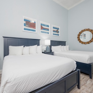 Relaxing guest bedroom featuring two plush queen beds, coastal artwork, and soft blue walls for a serene escape