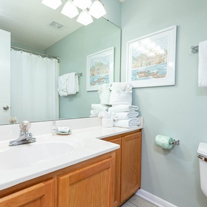 Brightly colored walls complement this guest bathroom featuring a large mirror and neatly stacked towels