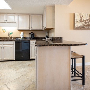 Modern kitchen features light cabinetry, granite countertops, Keurig and coffee maker, and a breakfast bar with seating
