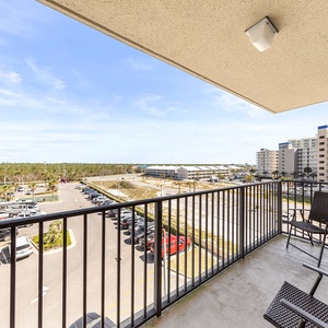 A private balcony offers seating and a view of the nearby beach and surrounding area, creating a relaxing outdoor space