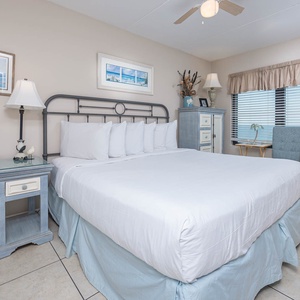 The master bedroom features a comfortable bed, stylish decor, and a lovely beachfront view through the large windows