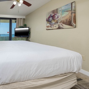 The master features a comfortable king bed, a flat-screen TV, and a lovely view of the beach from the balcony