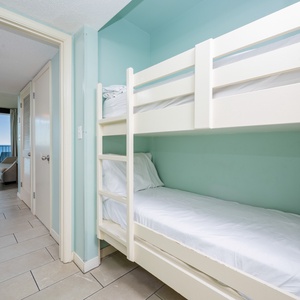 Cozy bunk beds provide a fun sleeping space for kids, with a view of the inviting living area and coastline beyond