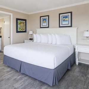 Master bedroom featuring a king bed with plush pillows, stylish artwork, and an ensuite bathroom
