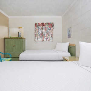 This cozy bedroom features two beds, colorful curtains, and a charming green cabinet, perfect for a relaxing stay