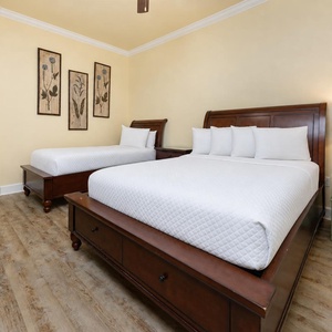 Comfortable guest bedroom featuring two beds, queen and twin, stylish decor, and warm wooden accents