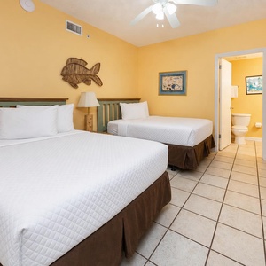 Rest comfortably in this cheerful guest room featuring two double beds, vibrant yellow walls, and charming coastal decor